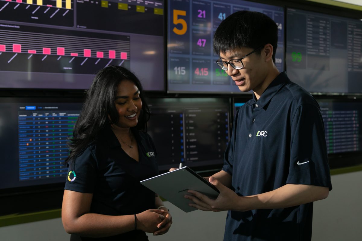 Woman and man standing in front of a wall of screens