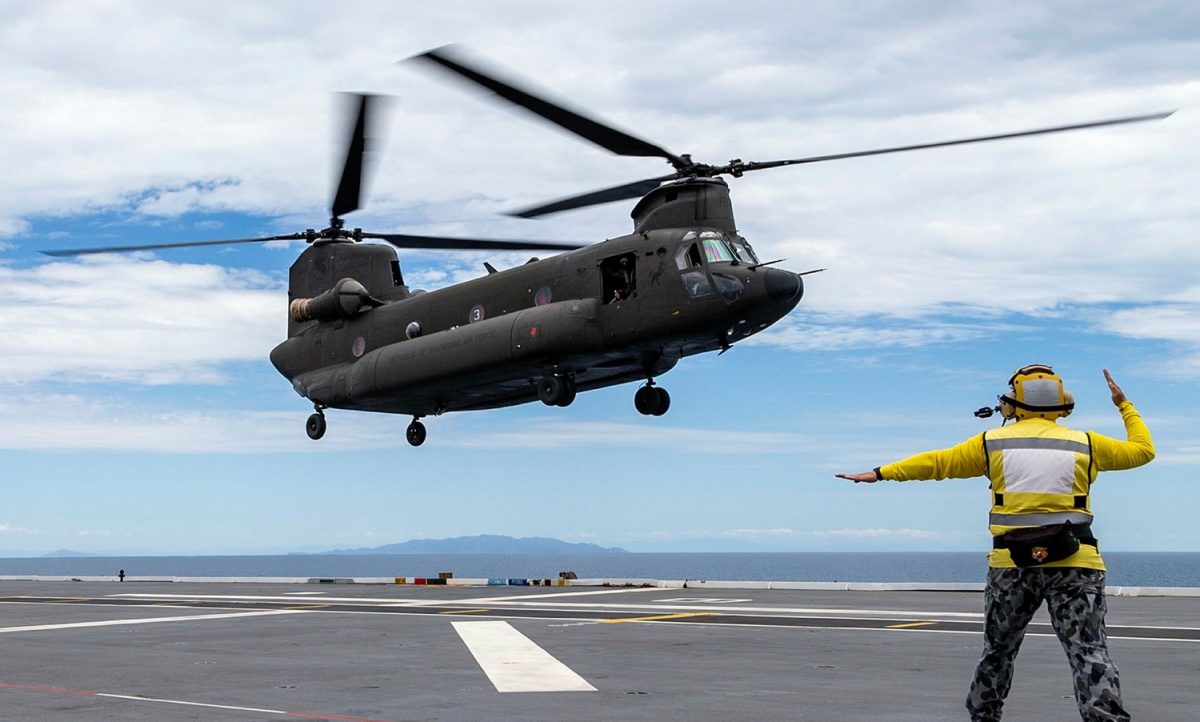helicopter being guided to landing on navy ship