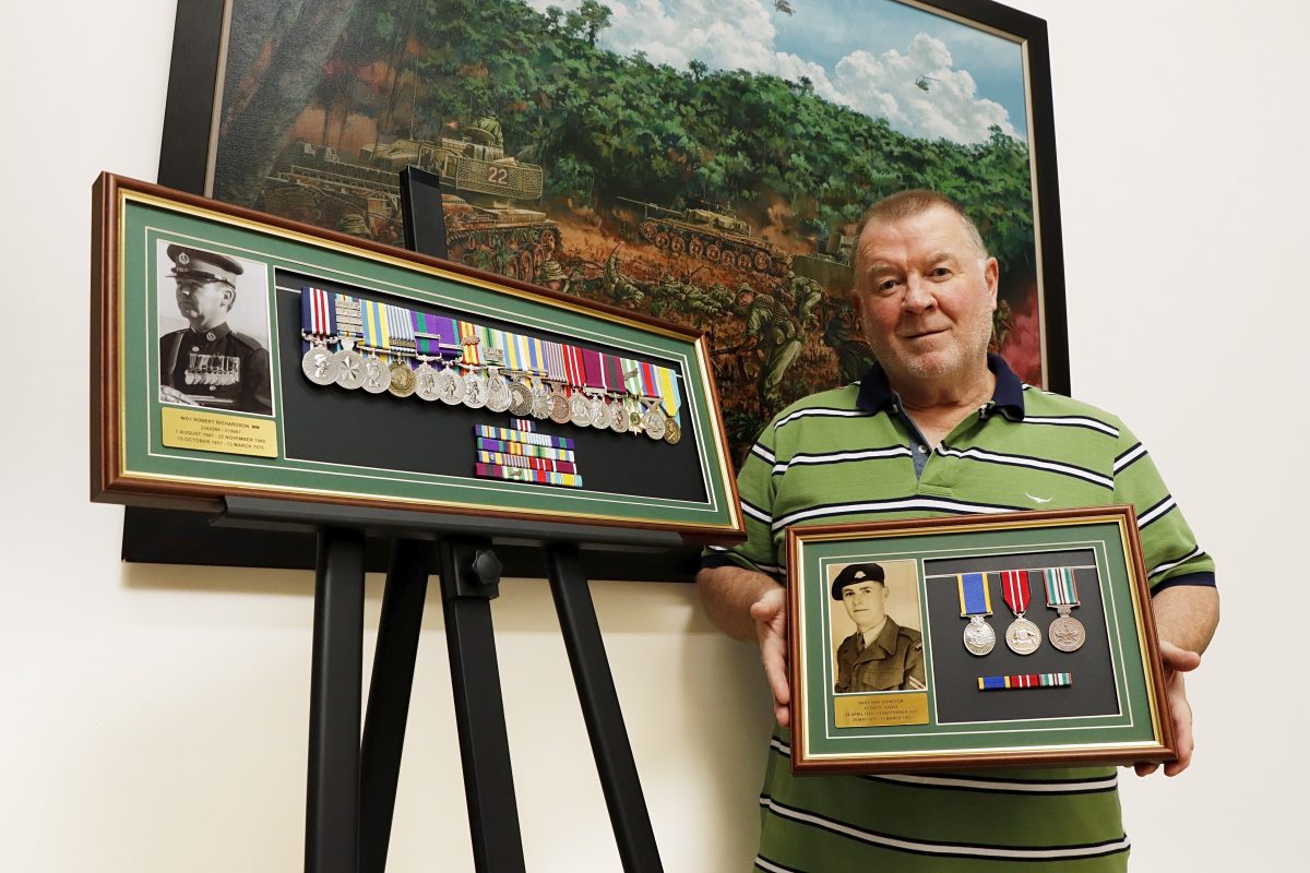 Craig Johnston holding framed medals 