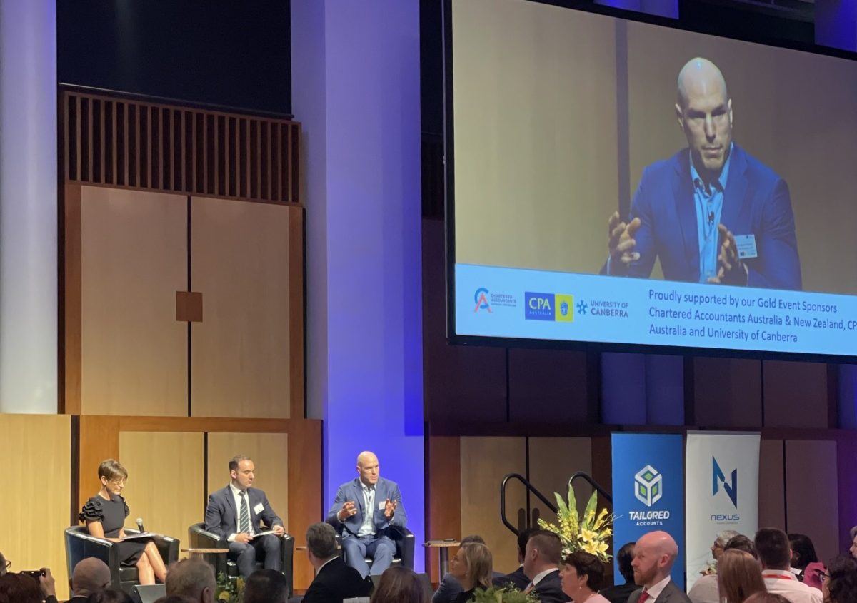 David Pocock on a large screen at a business breakfast