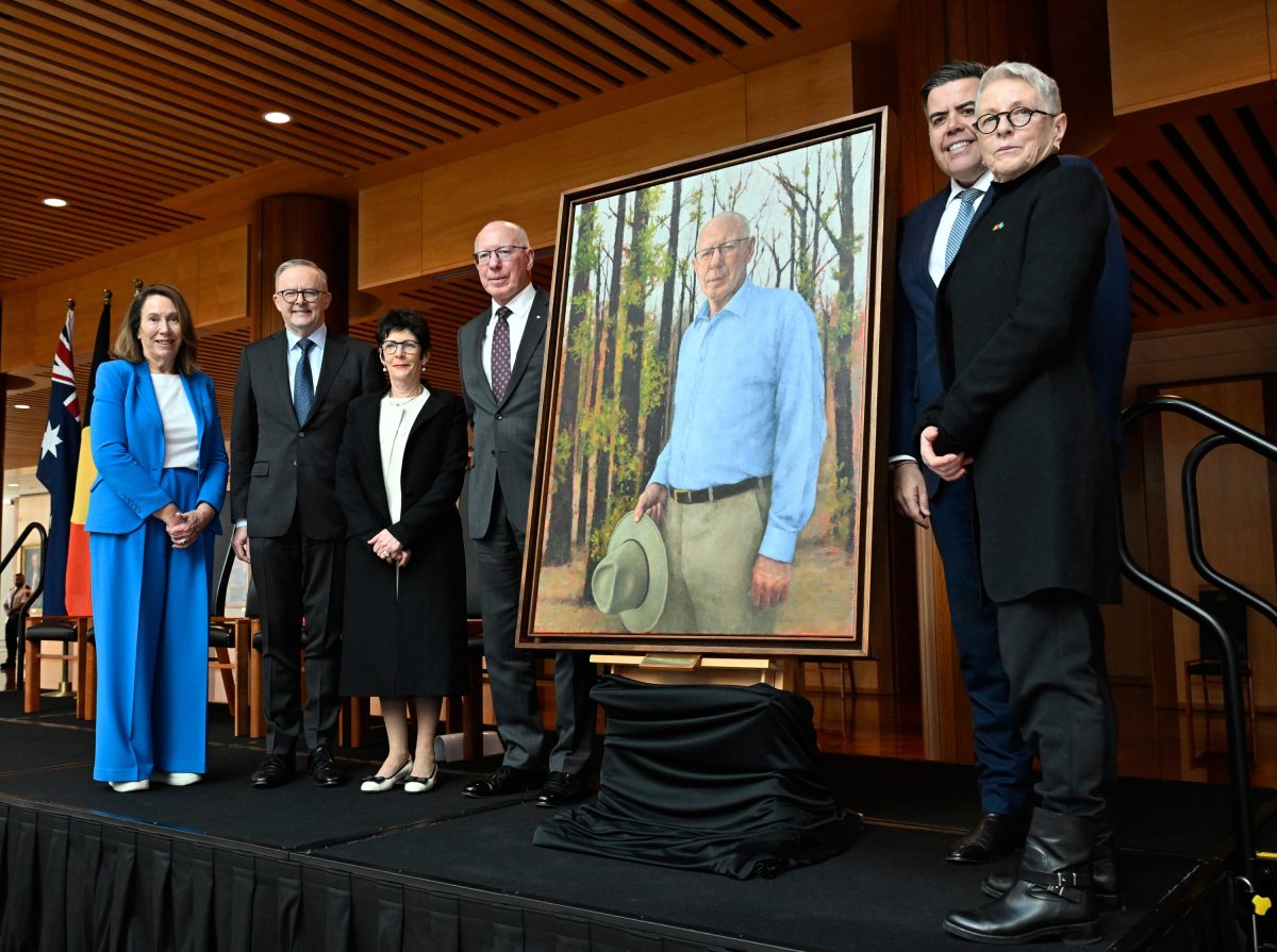 Six people standing in front of a portrait