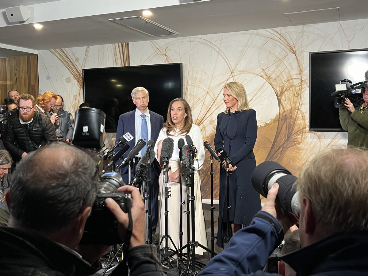 Three people standing behind microphones