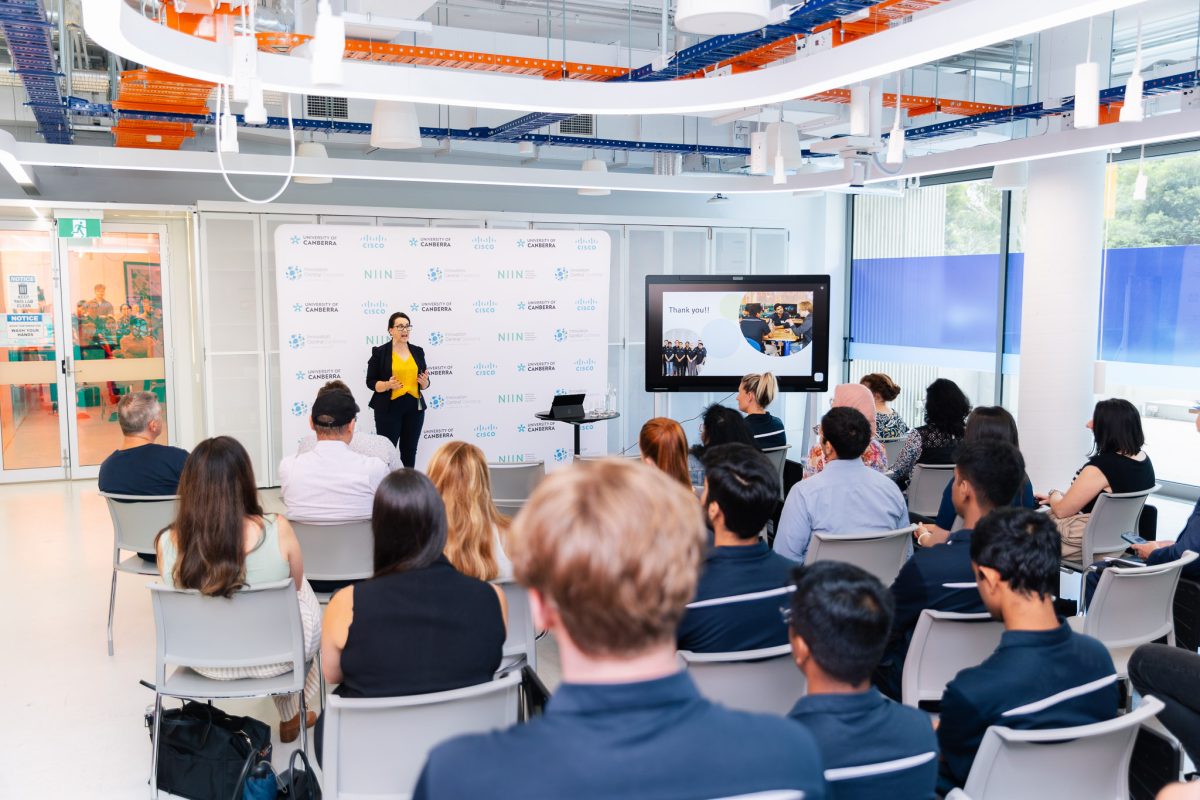 Classroom full of students being presented with a presentation on a TV.