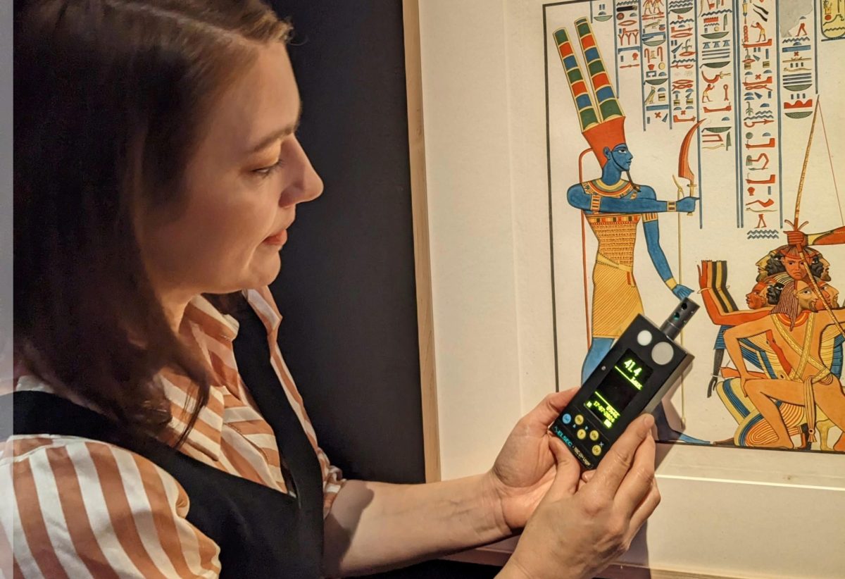 Woman taking light readings of museum art.