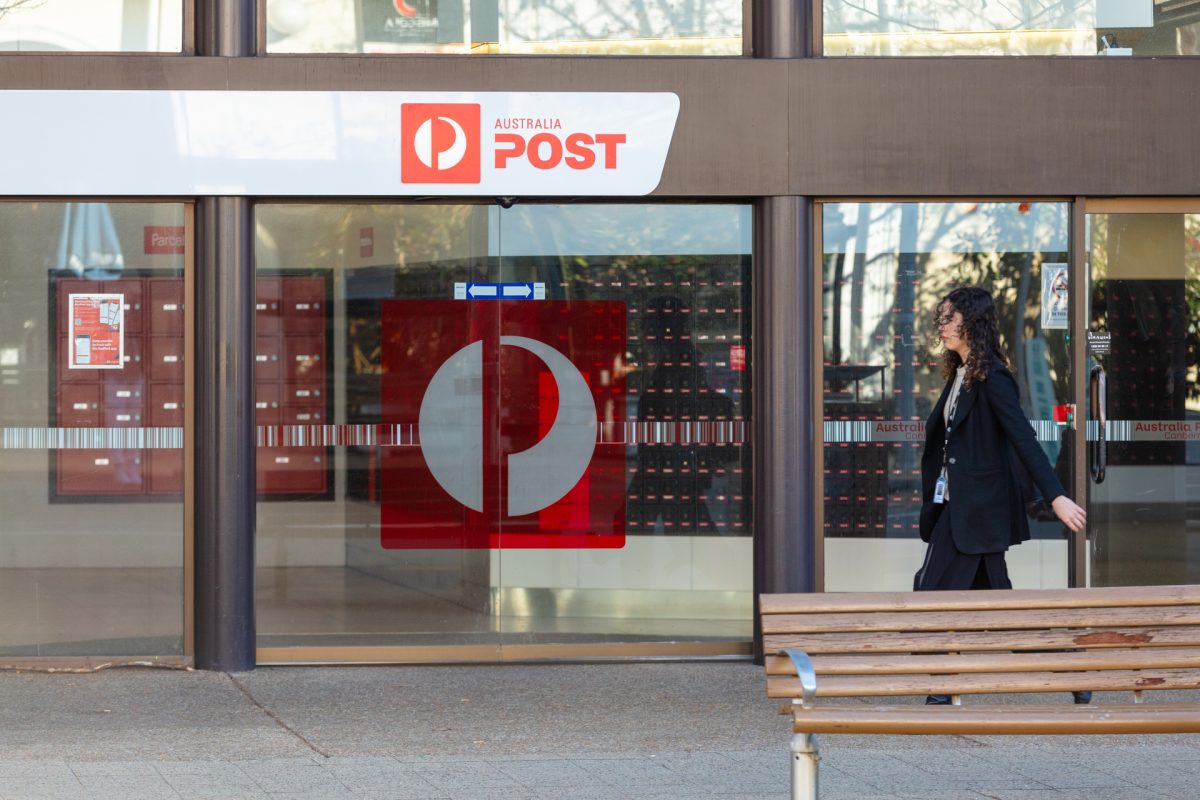 Woman walking past Australia Post shop