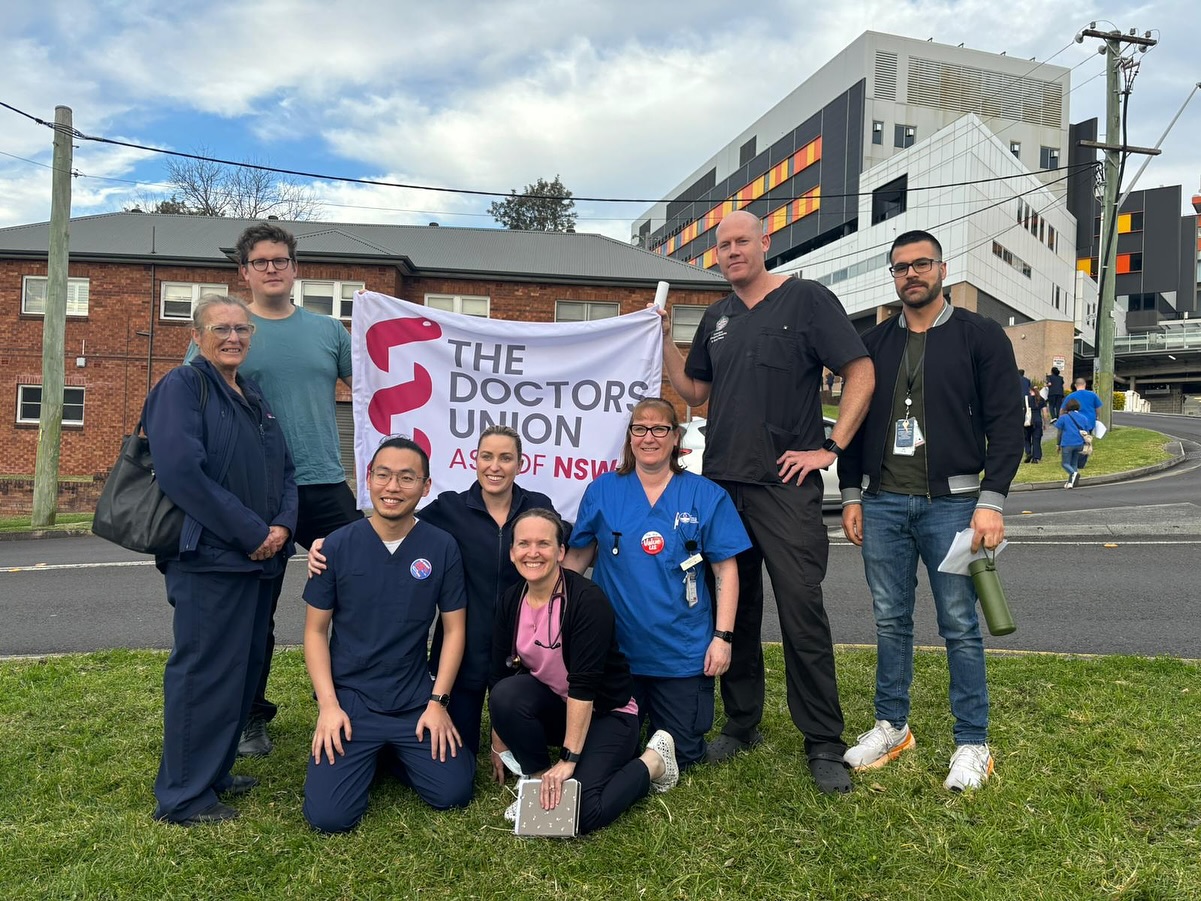 Group of doctors holding up a union flag outside a hospital