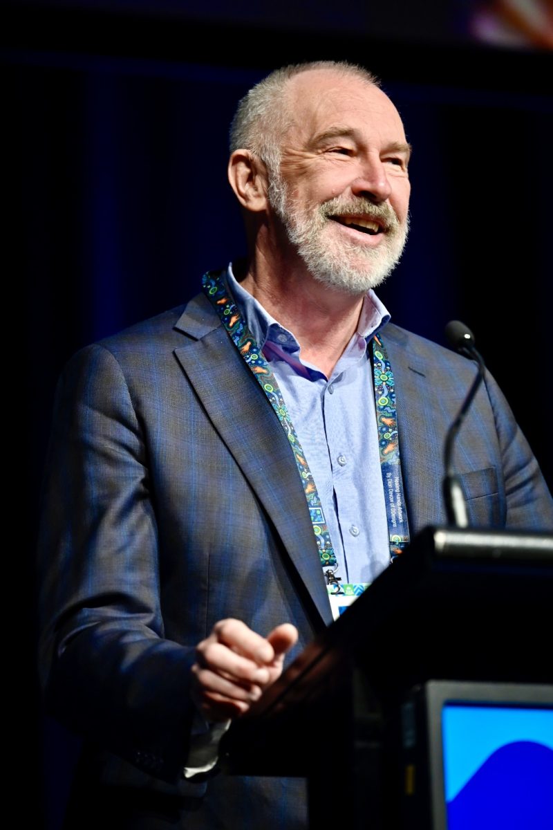 Smiling man at podium.