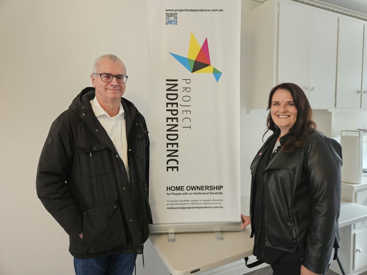 Two people standing next to Project Independence sign 