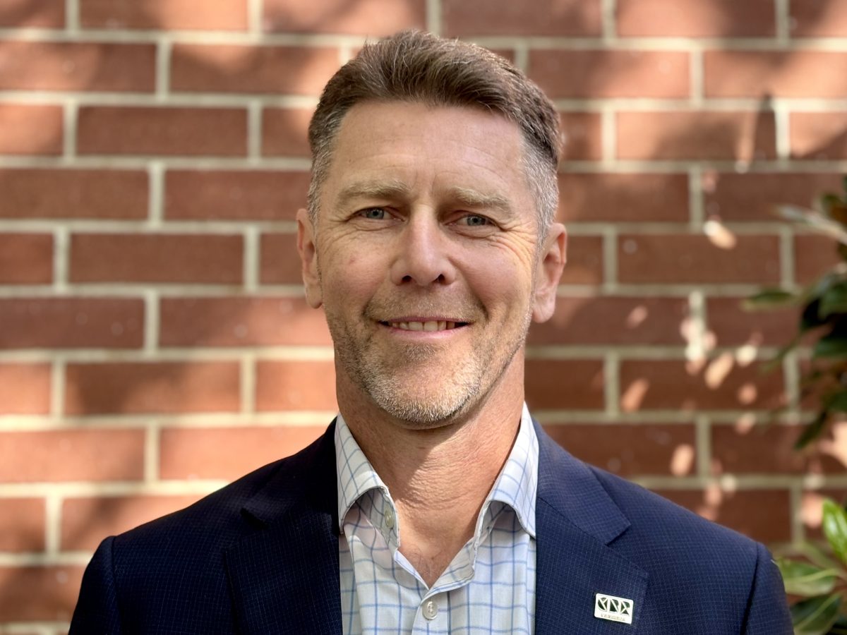 Headshot of man in front of brick wall.