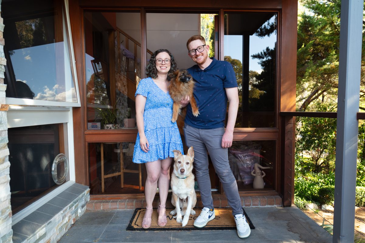 two people standing with their dogs at the front door of their home