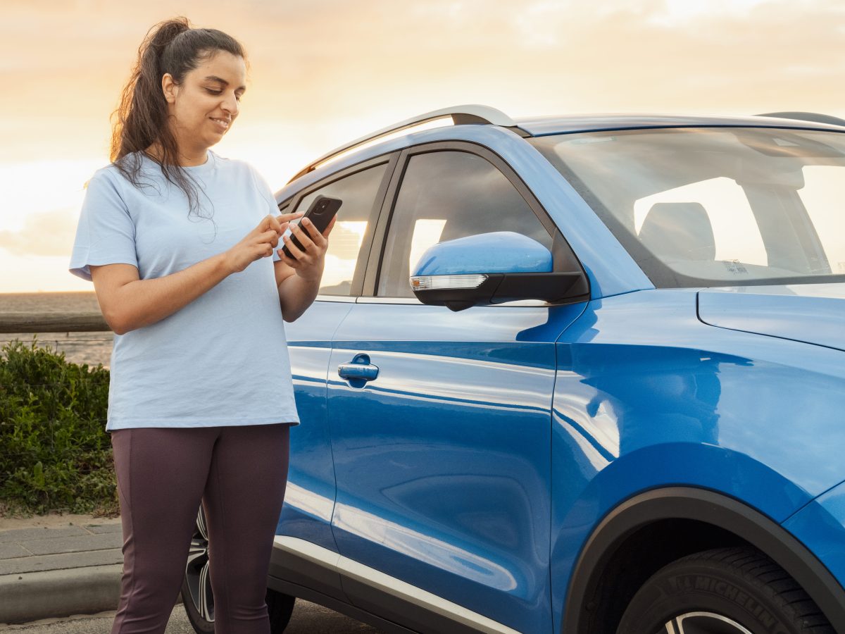 Lady on phone next to a blue car