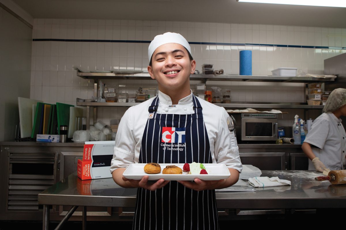 Student chef holding plate of dessert