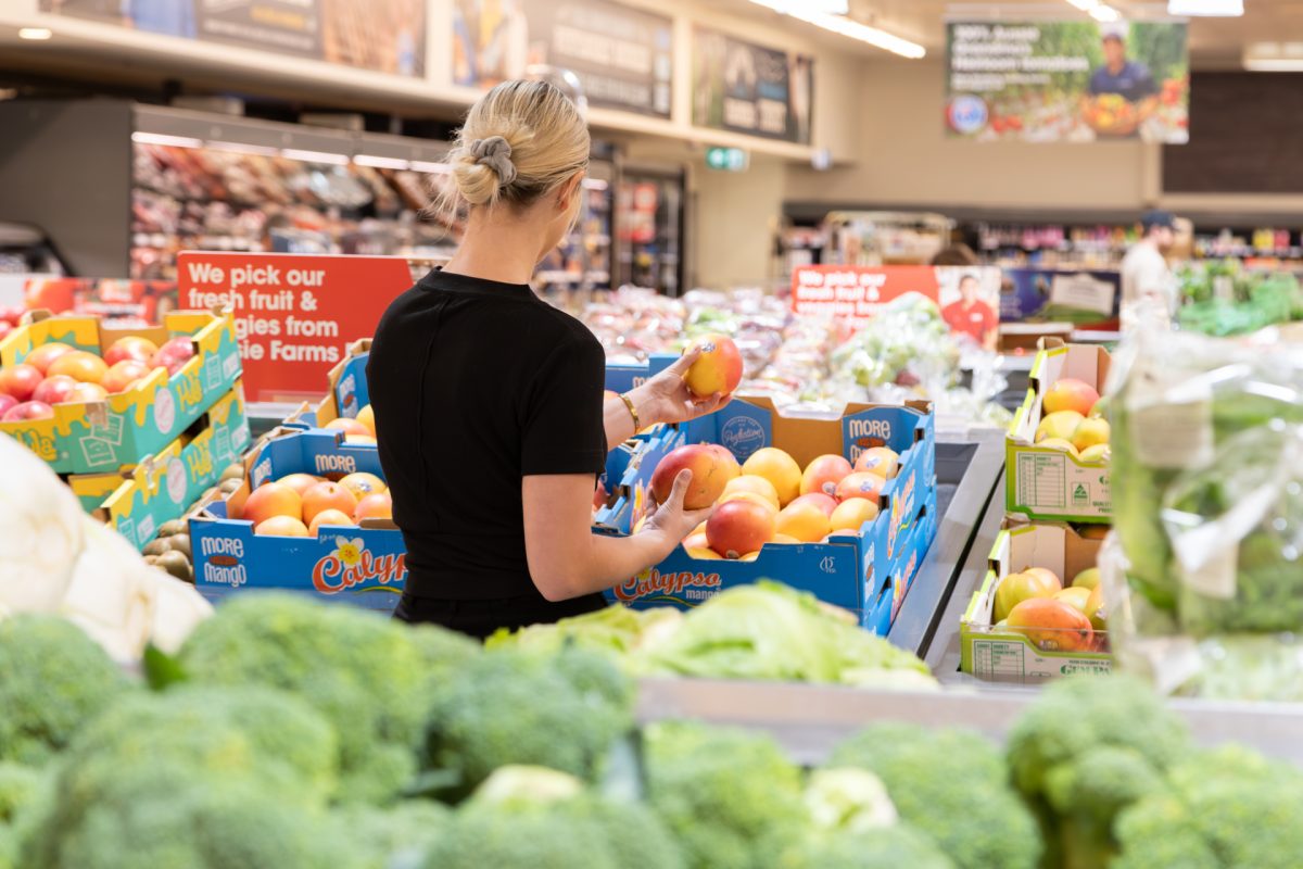 Woman handling mango in supermarket