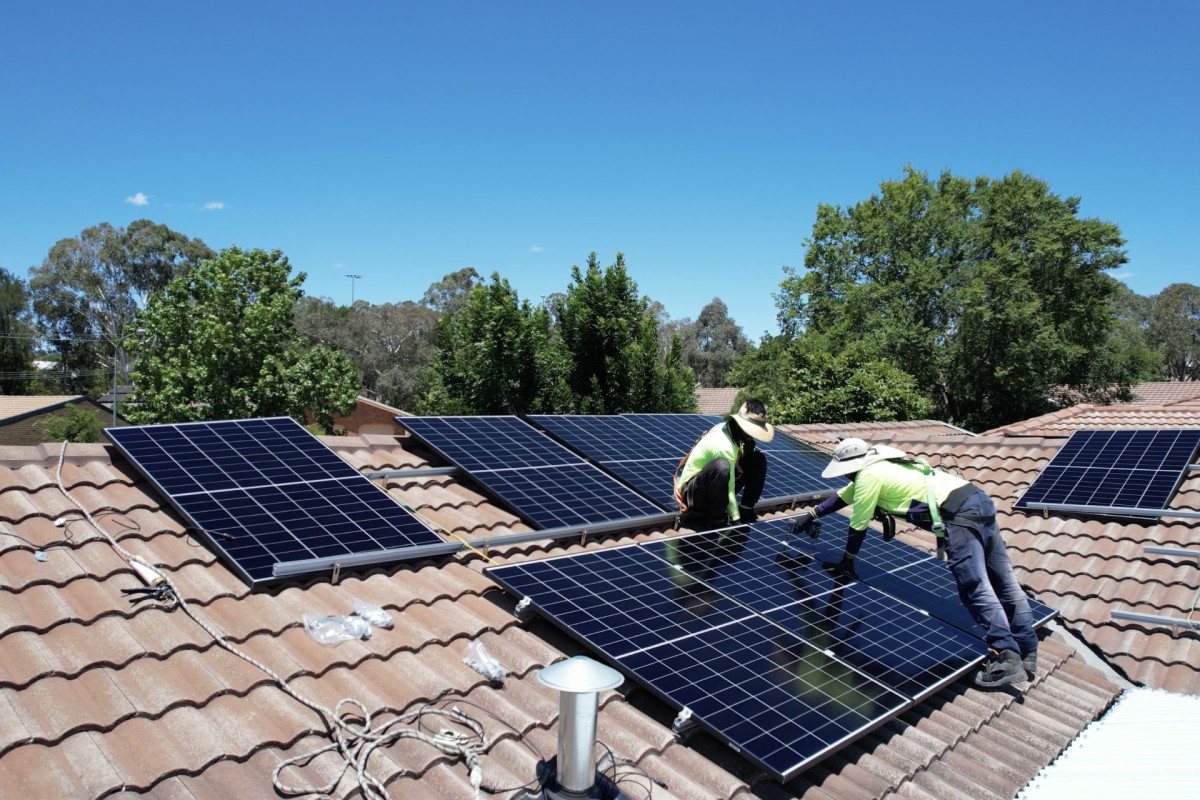 two people standing on a roof installing solar panels