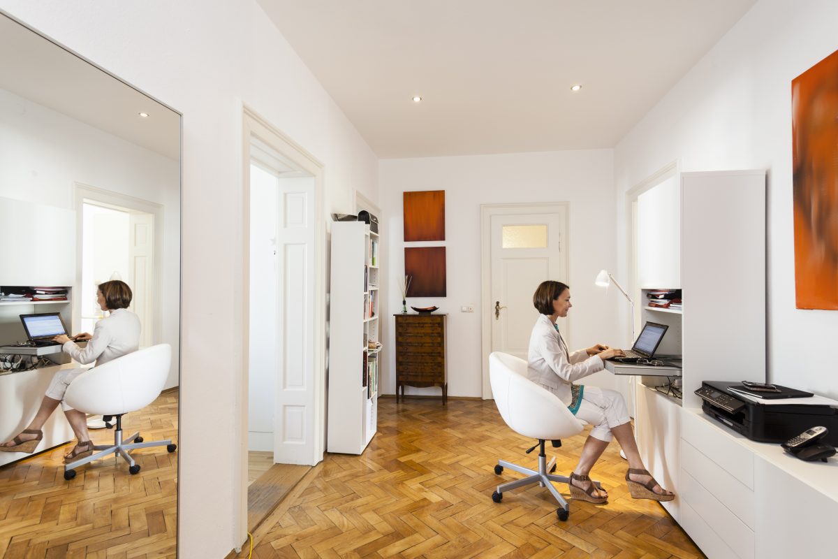 Mature businesswoman typing on laptop in apartment