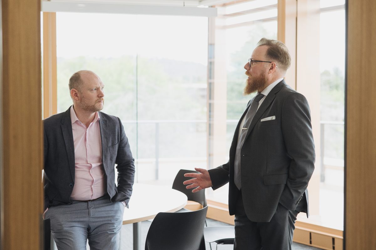 Two men in office talking.