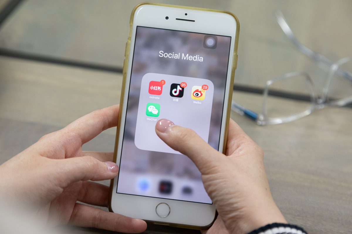 Hands holding iPhone with social media app screen