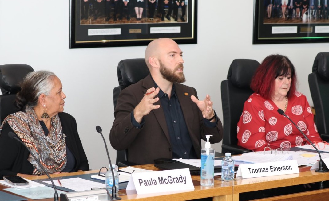 three people sitting at a long desk