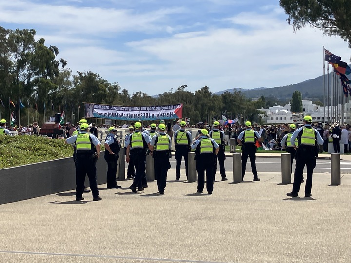 Behind view of police watching protesters.