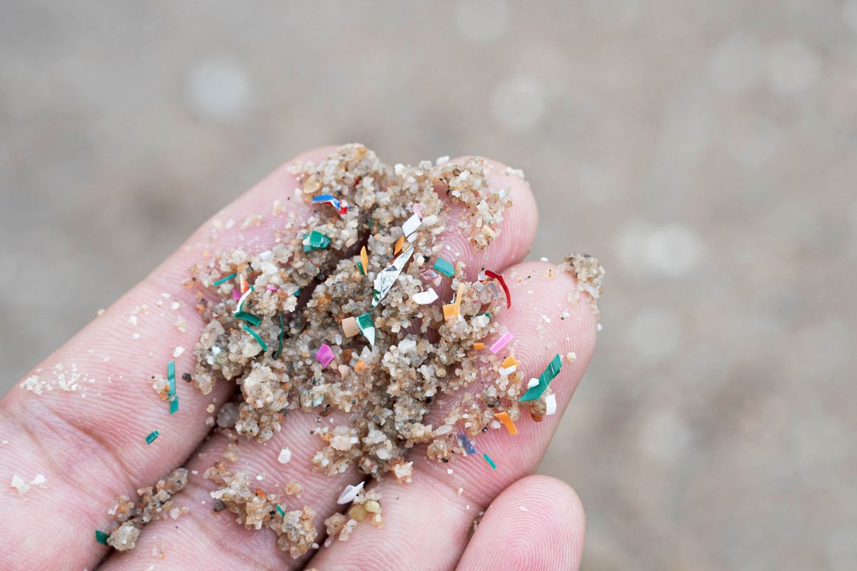Hand holding sand mixed with microplastics