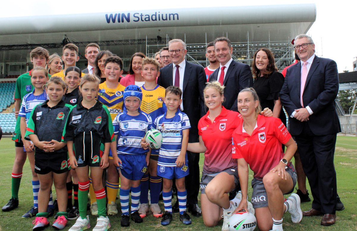 a group of adults with junior and women's rugby league players at a stadium 