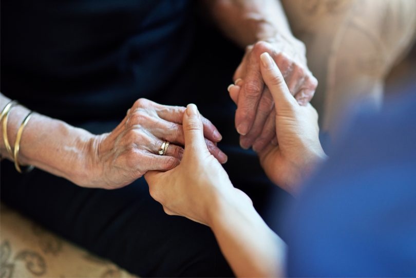 Nurse holding elderly patient's hands