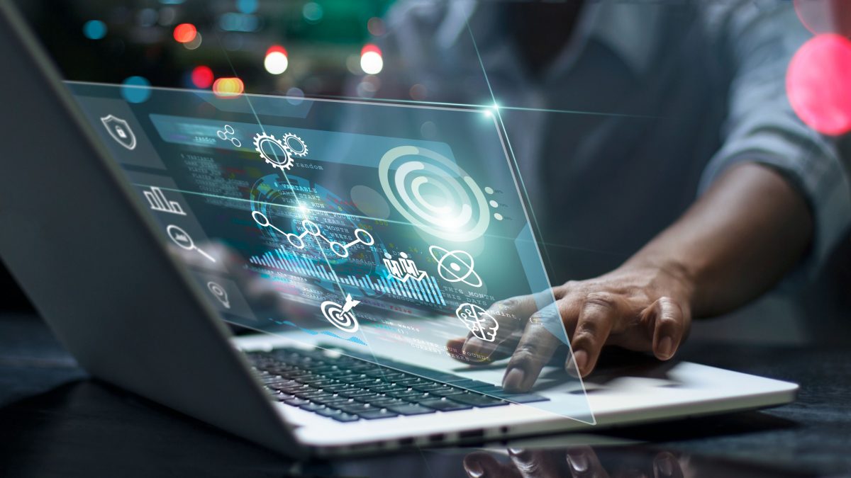 man using a laptop, with a screen showing symbols and graphs