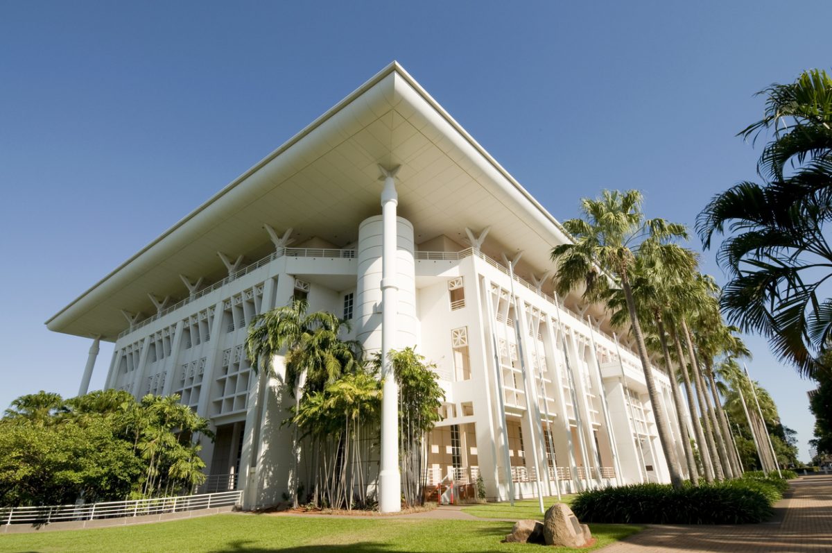 The Northern Territory parliament building in the day with palm trees surrounding it.