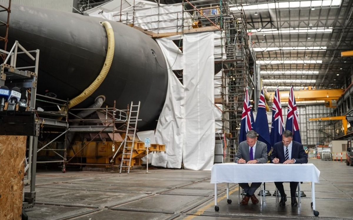 two man at an official signing near a submarine