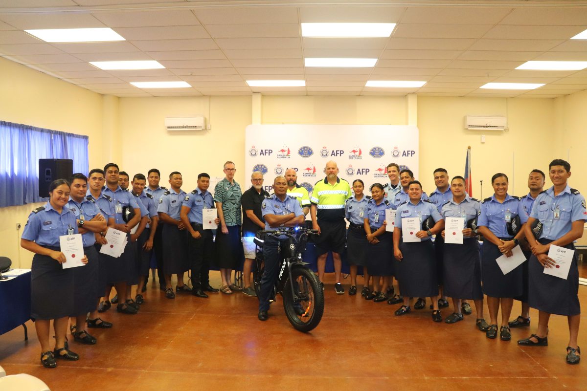 Group of Samoan police officers standing with their program certificates and an e-bike in the middle.