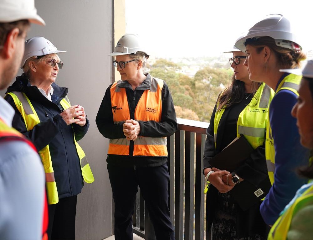 Jacinta in high-vis with other project workers on a balcony of one of the social housing apartments in Prahran.