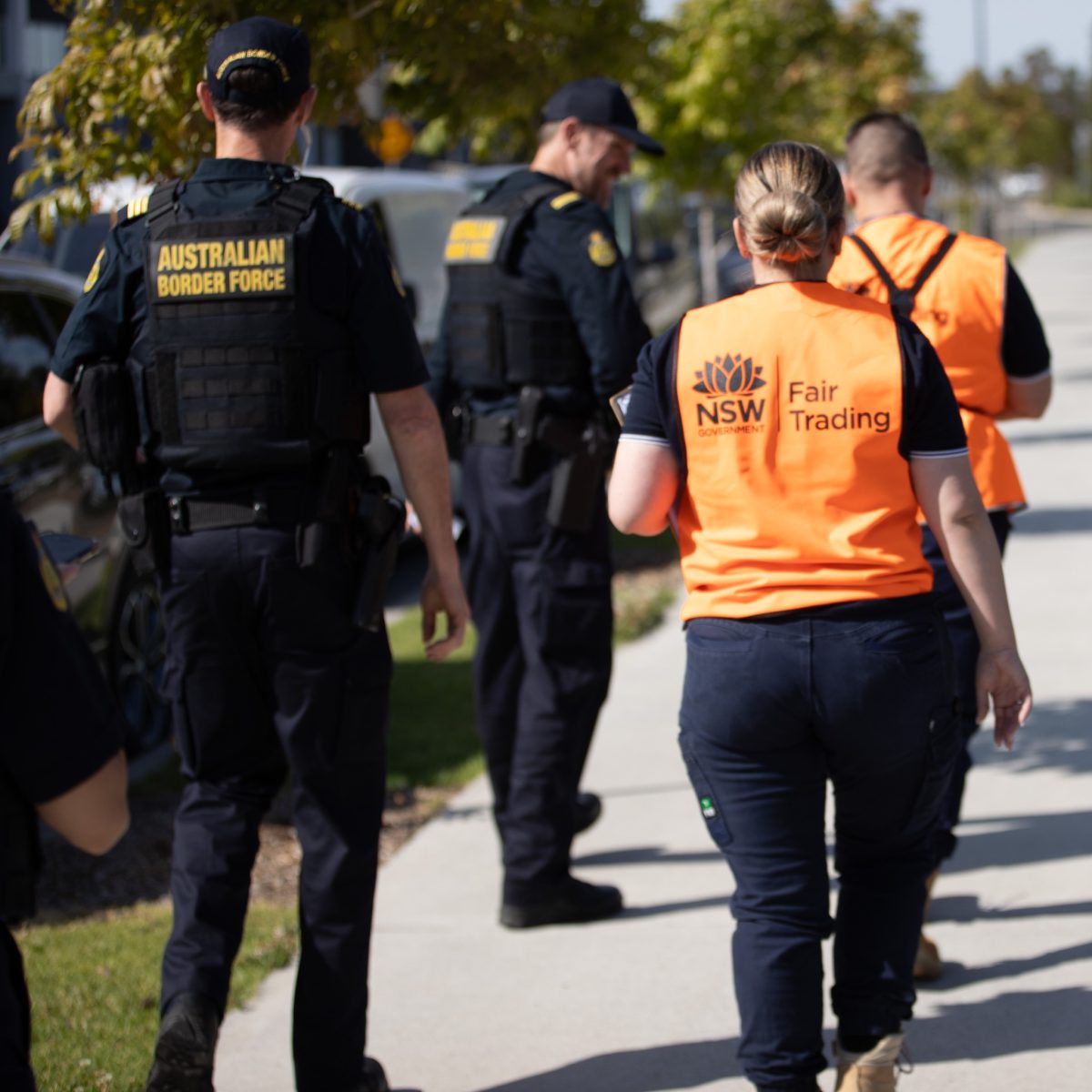 Fair Trading officers walking with Australian Border Force officers on a sidewalk.