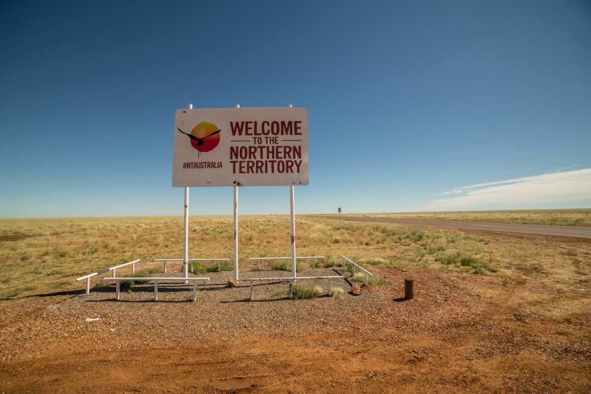"Welcome to the Northern Territory" sign standing beside the highway in the outback.