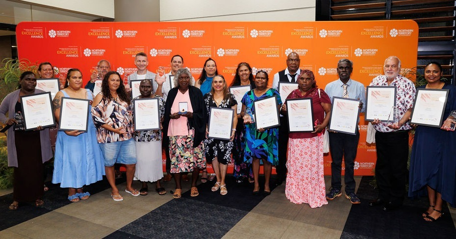A group of the award recipients holding their certificates in front of an NT Health banner.