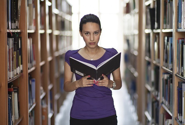 tertiary student looking at book in library