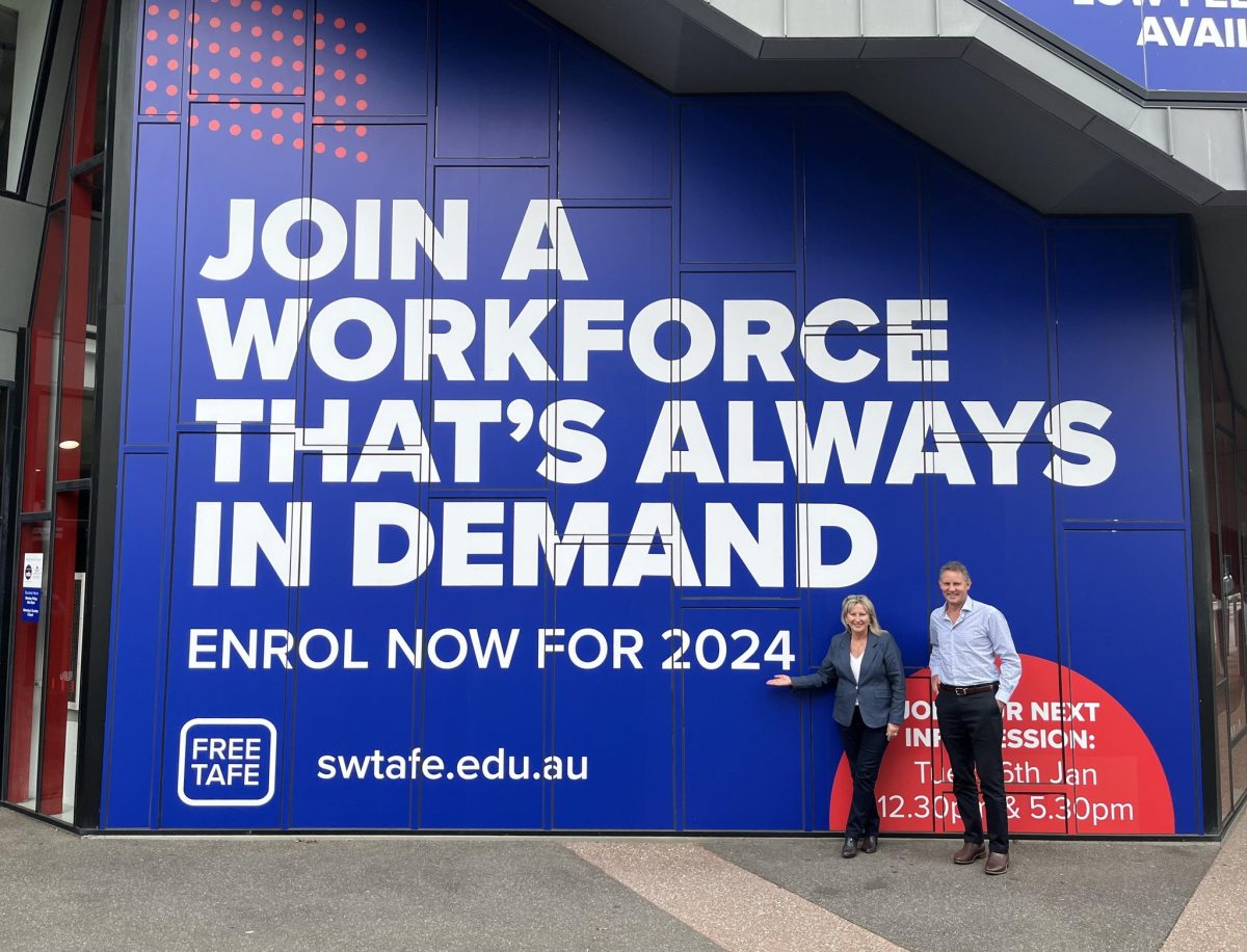 man and woman in front of large TAFE sign