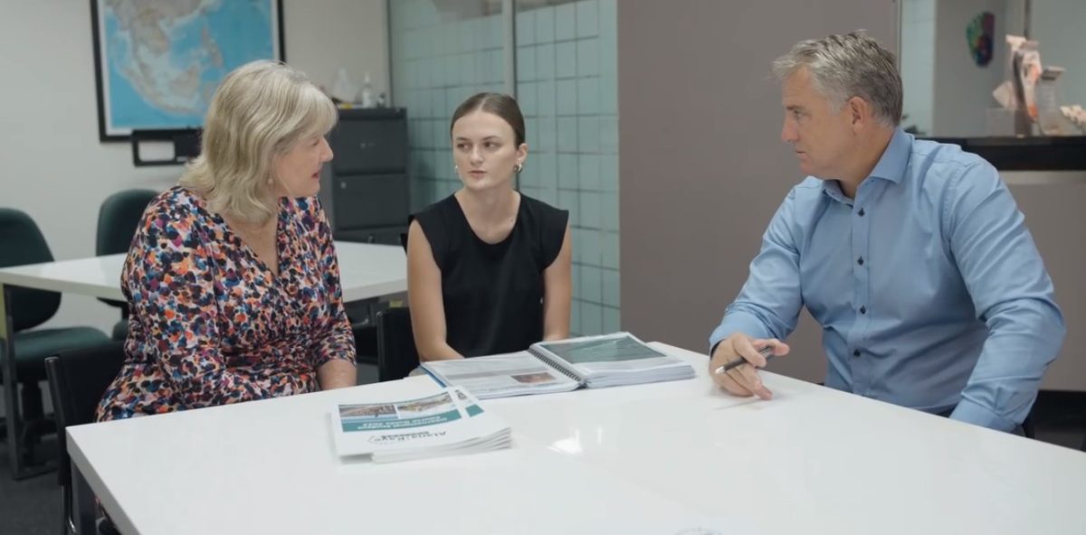 Three people sat around a table talking.