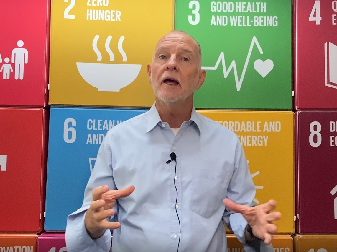 Terry explaining the ACDC in front of a wall with each of the UN Sustainable Development goals.