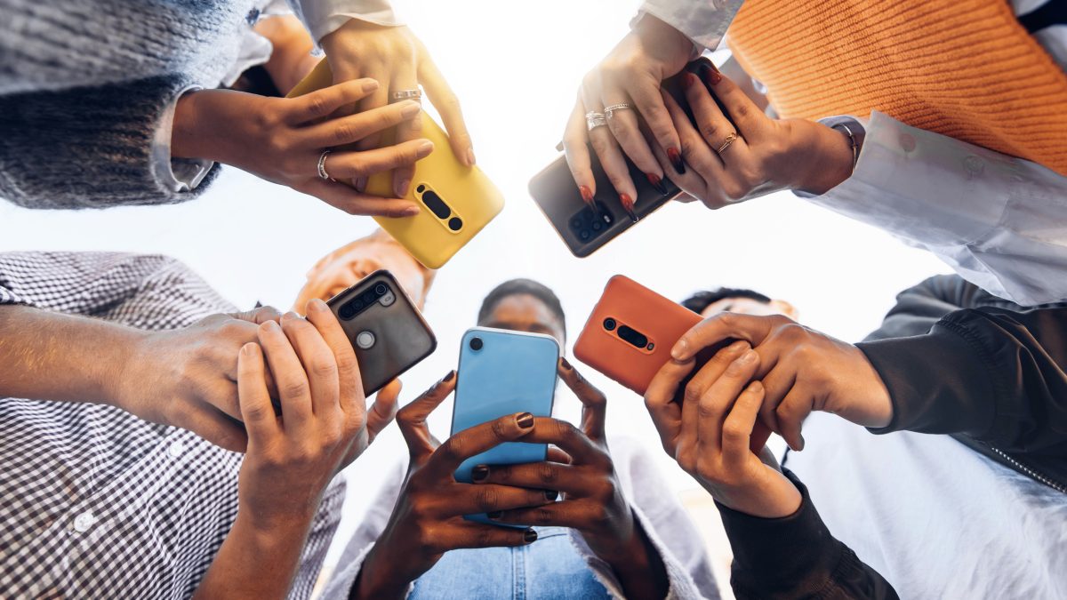 Teens in circle holding smartphones 