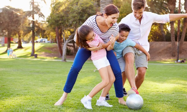 family playing with a soccer ball in the park