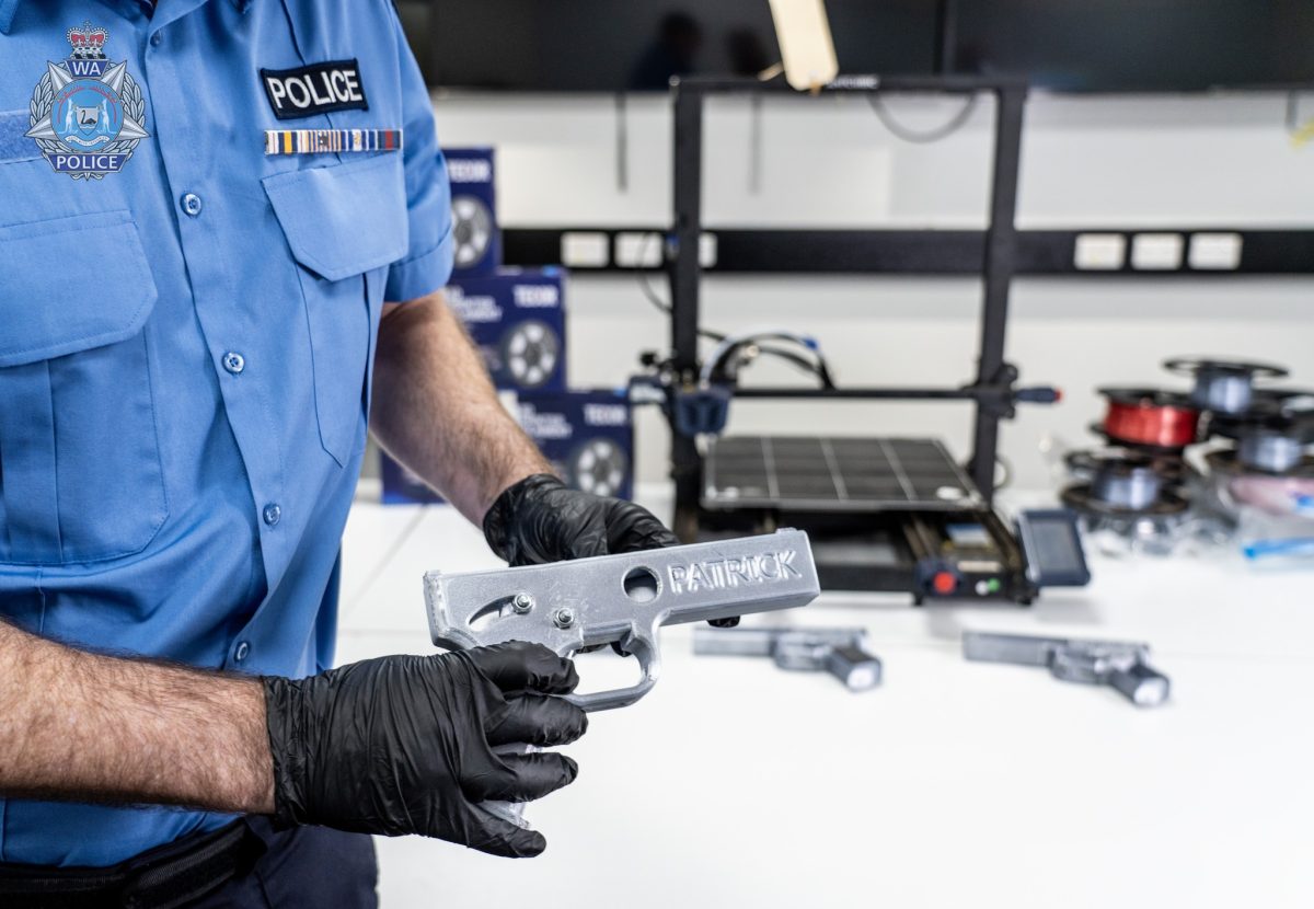 A police officer holding a 3D-printed gun labelled 'PATRICK'.