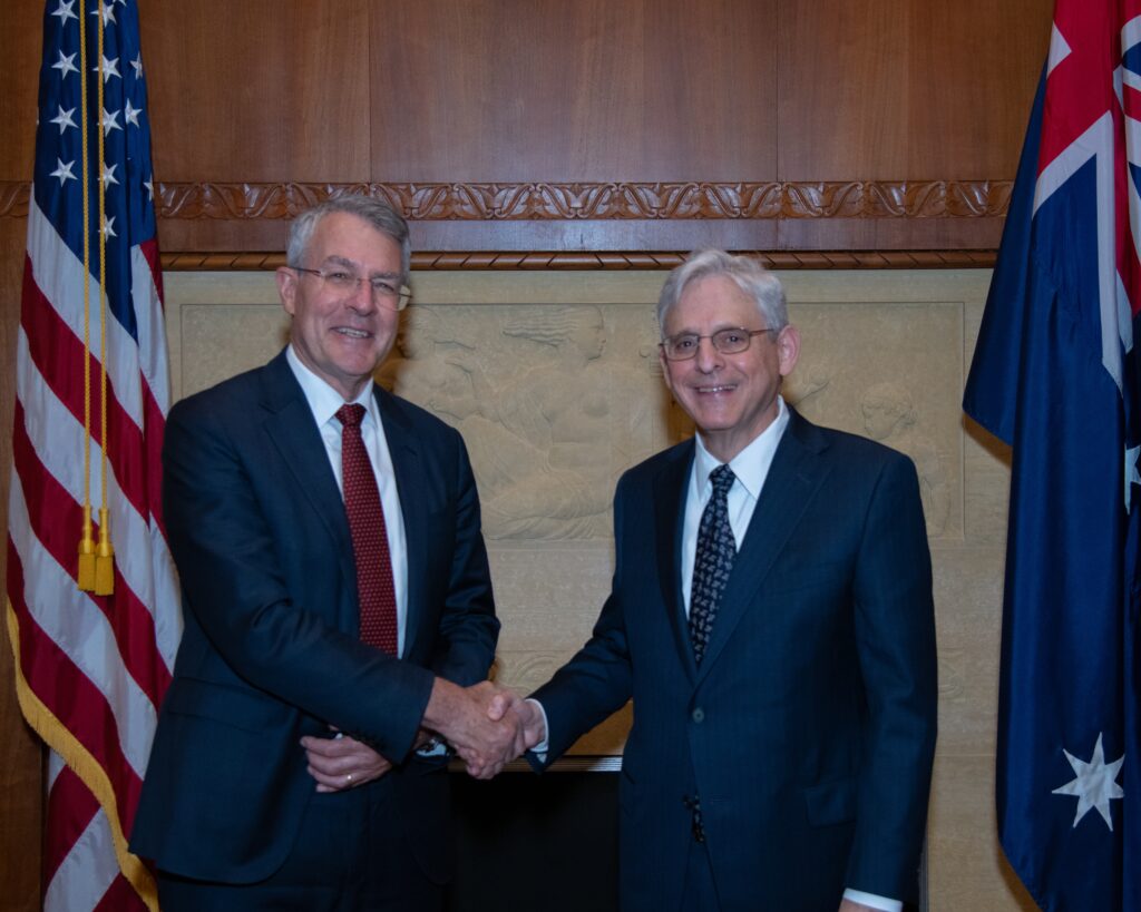 Mark Dreyfus and his US counterpart Merrick B. Garland shaking hands with an American and Australian flag astride eachother.
