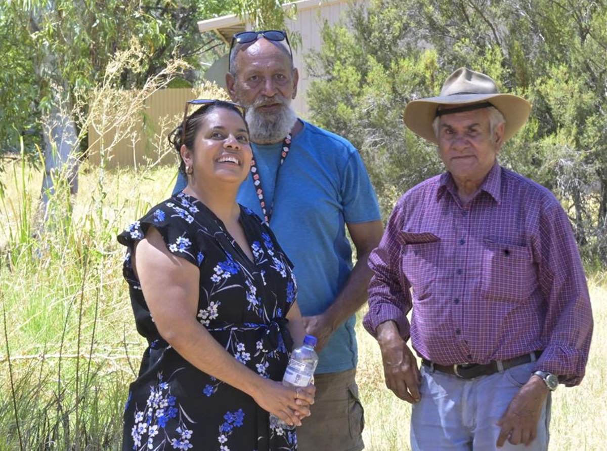 three people standing in bushland