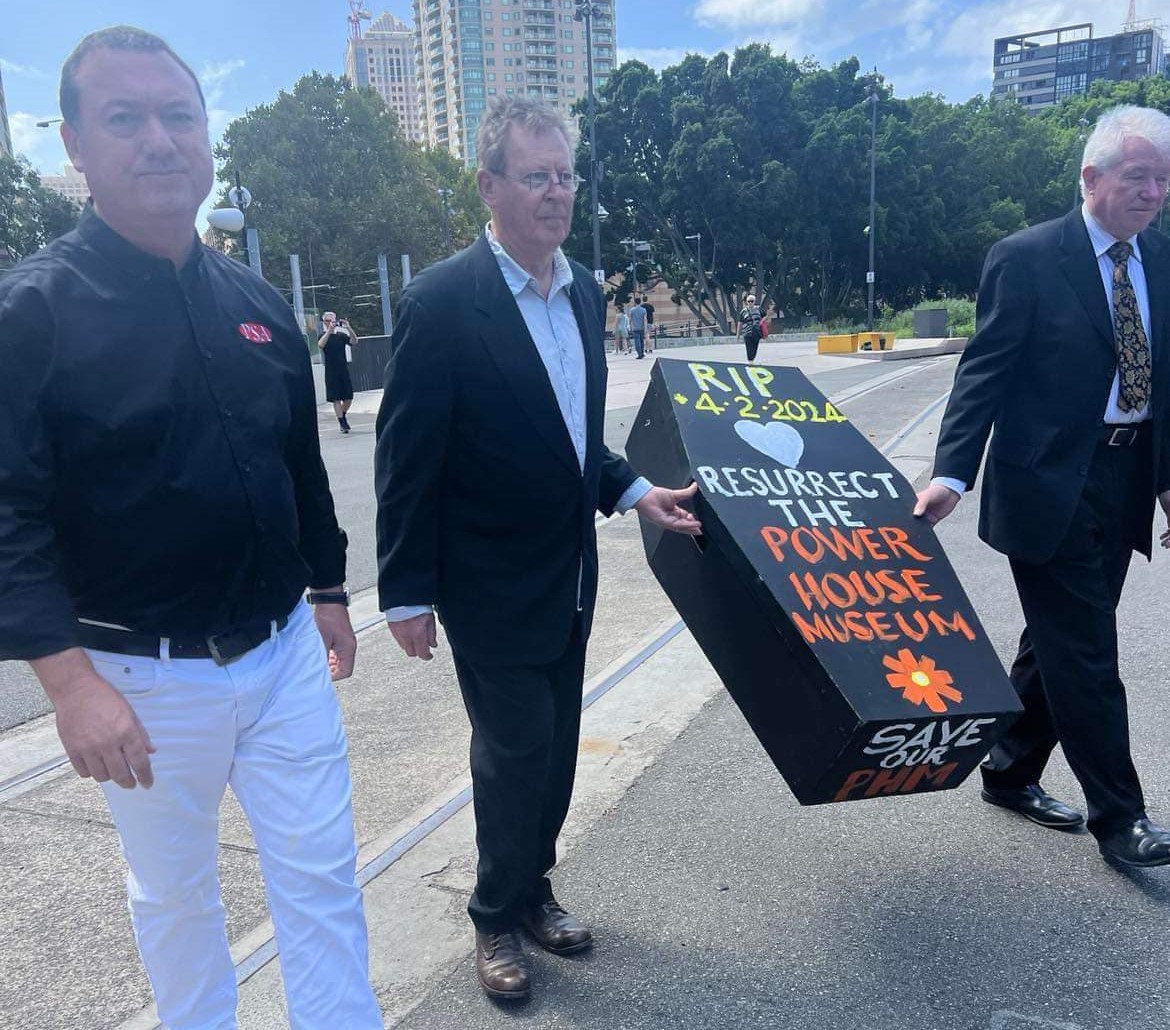 three men protesting with a fake coffin