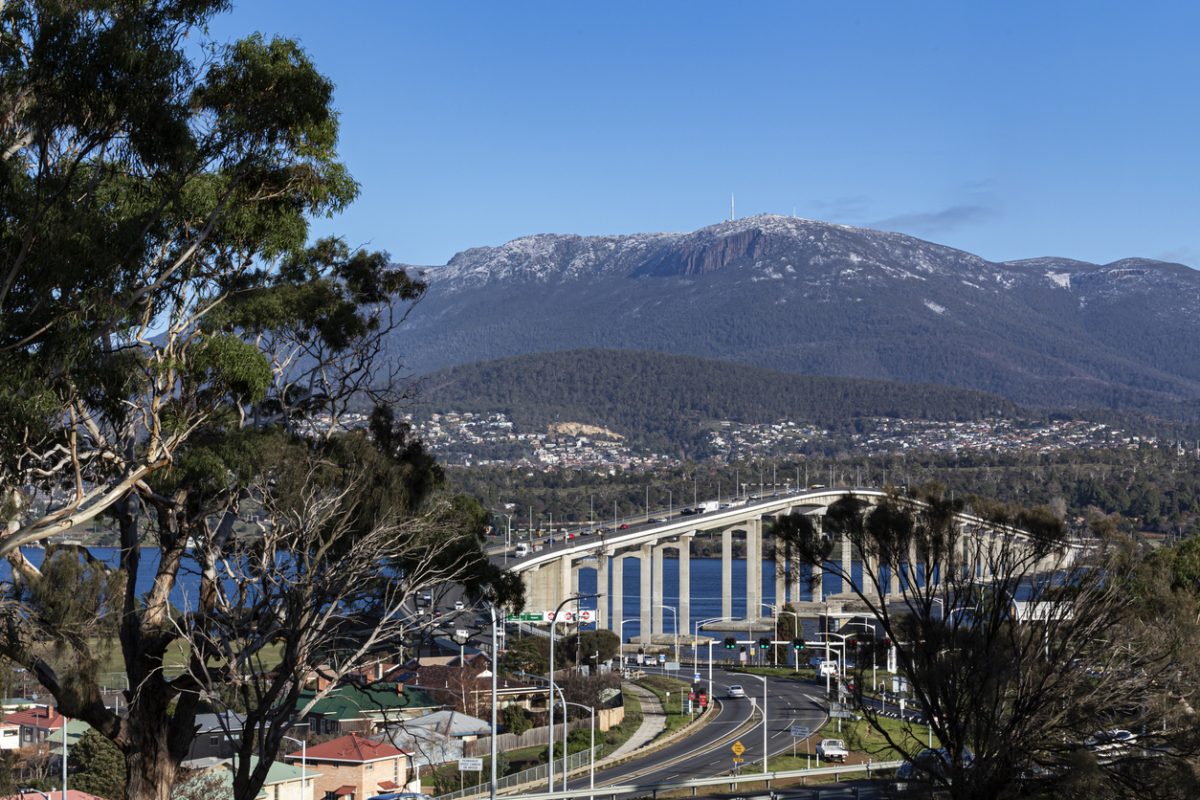 View of Mount Wellington Hobart with partial view of the Tasman Bridge, with some trees in the foreground, Hobart, Tasmania, Australia.