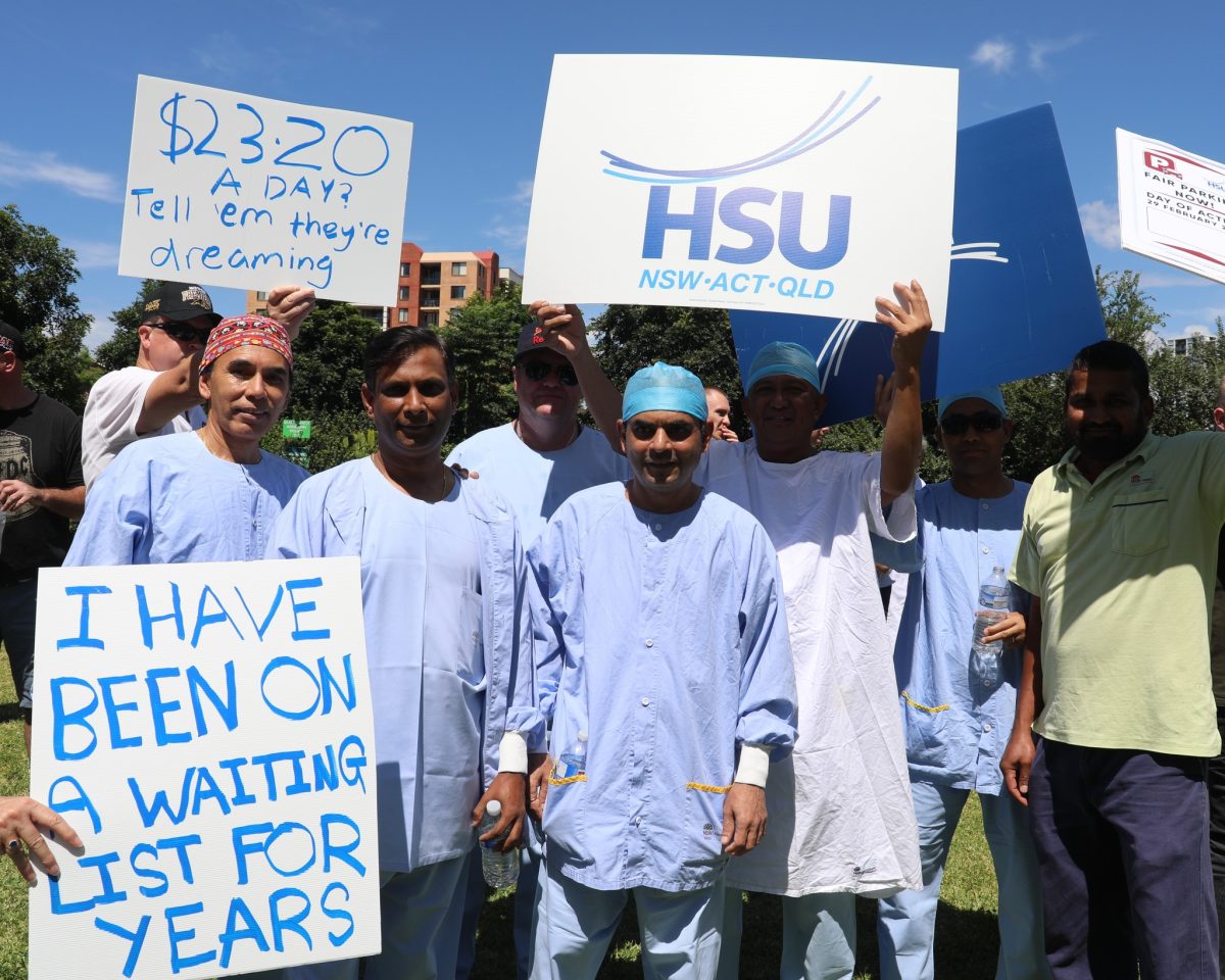 A group of doctors in their surgery smocks protesting outside Westmead hospital with signs about parking fees.
