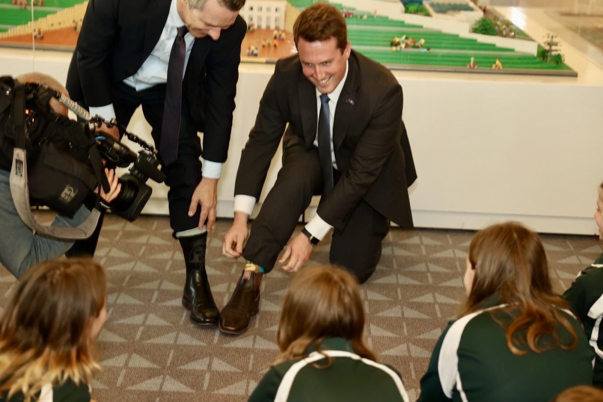 Two politicians showing off their socks to schoolchildren at Parliament House