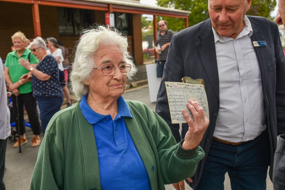 Older woman holding up a bank passbook at a bank branch closure protest