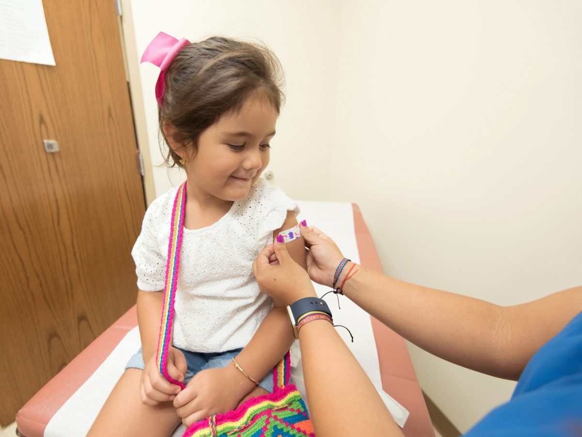 young girl having a Band-Aid put on her arm after vaccination