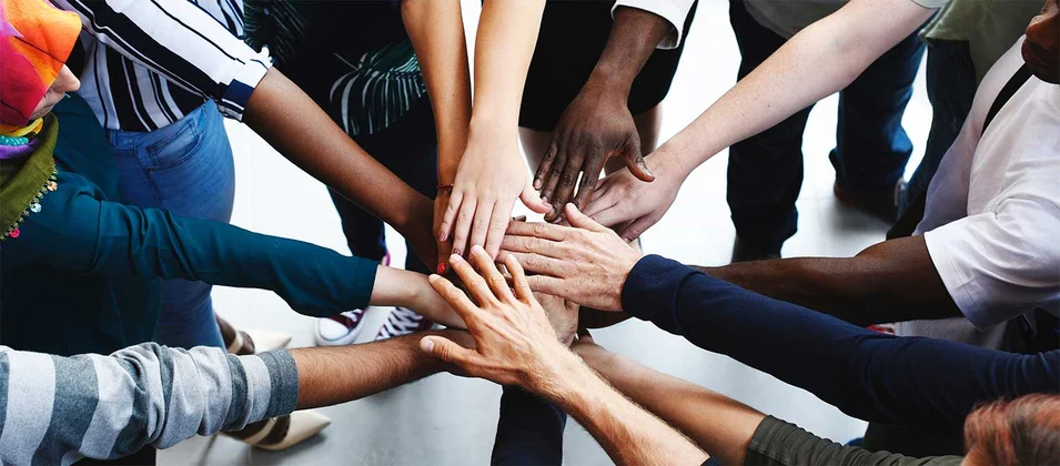 group of people in a circle with outstretched hands touching